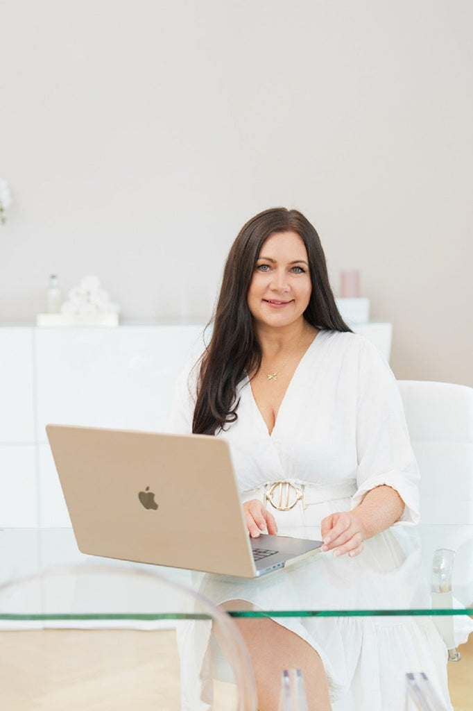 Monique Pfenniger Inhaberin von MoniQue Cosmetique in Dresden mit Laptop an einem Glasschreibtisch